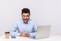 Crazy funny businessman sitting office workplace with laptop on desk, showing his tongue, looking at camera Royalty Free Stock Photo