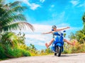 Crazy funny woman with flying hair riding a motorbike on a blue sky and green tropics background. Young bizarre girl Royalty Free Stock Photo