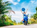 Crazy funny woman with flying hair riding a motorbike on a blue sky and green tropics background. Young girl with dark Royalty Free Stock Photo