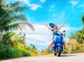 Crazy funny woman with flying hair riding a motorbike on a blue sky and green tropics background. Young girl with dark Royalty Free Stock Photo