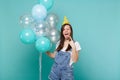 Crazy girl in birthday hat showing tongue horns up heavy metal rock sign celebrating, hold colorful air balloons Royalty Free Stock Photo