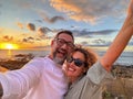 Crazy happy couple of tourist taking selfie picture at the beach with amazing sunset in background. Beach and ocean lifestyle Royalty Free Stock Photo