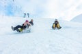 Crazy happy friends having fun with sledding on snow high mountains - Young millennial people making luge competition at white Royalty Free Stock Photo