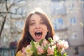 Crazy and happy young girl looking at the camera with happiness and emotions in her eyes holding a big bouquet of Royalty Free Stock Photo
