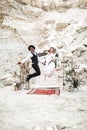 Crazy hippy multi rational Wedding couple dressed in boho style are jumping before the wedding arch in canyon outdoors Royalty Free Stock Photo