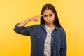 Crazy idea! Portrait of girl in denim shirt showing stupid gesture with finger near head and blaming fool