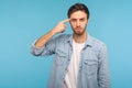 Crazy idea! Portrait of man in denim shirt showing stupid gesture, looking at camera with condemnation Royalty Free Stock Photo