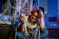 Crazy mad computer engineer wrapped in wires and cables in server room