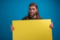 Crazy male making funny faces while displaying pirced tongue and holding a yellow banner