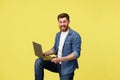 Crazy smiling man with beard holding laptop on leg and looking at camera. Studio shoot Royalty Free Stock Photo