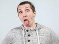 Crazy man showing his tongue with wide opened eyes, grey background Royalty Free Stock Photo