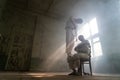 A crazy man in a straitjacket is tied to a chair in an abandoned old clinic and the other insane man coming closer with