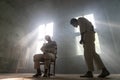 A crazy man in a straitjacket is tied to a chair in an abandoned old clinic and the other insane man coming closer with