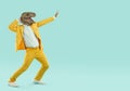 Crazy man in yellow suit and funny dinosaur mask dancing on turquoise copy space background