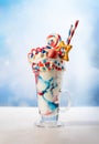 Crazy milk shake with ice cream,whipped cream, marshmallow,cookies and colored candy in glass. Sweet dessert for Fourth of July.