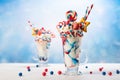 Crazy milk shake with ice cream,whipped cream, marshmallow,cookies and colored candy in glass. Sweet dessert for Fourth of July.