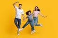 Crazy Offer. Funny Arab Family With Little Daughter Jumping Over Yellow Background Royalty Free Stock Photo