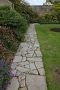 A crazy paving walkway between a flower bed and a lawn in an English country garden Royalty Free Stock Photo