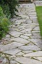 A crazy paving walkway between a flower bed and a lawn in an English country garden Royalty Free Stock Photo