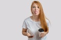 Crazy redhead woman with coffee and smart phone showing her tongue