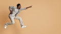 Crazy Sales. Emotional black man pointing aside while jumping over beige background Royalty Free Stock Photo