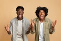 Two Excited Happy Black Guys Raising Hands And Opening Mouth In Amazement