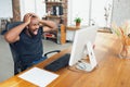 Young man, businessman working in office, looking on computer screen, monitor, with blank white sheet, whiteboard near Royalty Free Stock Photo