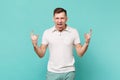 Crazy screaming young man in casual clothes showing horns up gesture, heavy metal rock sign isolated on blue turquoise Royalty Free Stock Photo