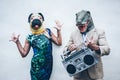 Crazy senior couple dancing for party wearing t-rex and chicken mask - Old trendy people having fun listening music with boombox Royalty Free Stock Photo