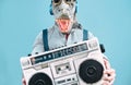 Crazy senior man wearing t-rex mask and listening to music holding vintage boombox stereo outdoor Royalty Free Stock Photo