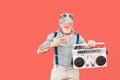 Crazy senior man wearing t-rex mask while listening to music holding vintage boombox stereo outdoor