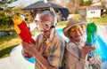 Crazy senior people have fun on vacation playing with water gun