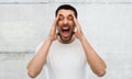 Crazy shouting man in t-shirt over gray wall