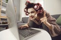 Crazy smiling mad housewife sitting font of laptop screen with raised finger