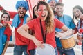 Crazy sport fans playing drums and screaming while supporting their team - Focus on center woman Royalty Free Stock Photo