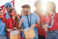 Crazy sport fans playing drums and screaming while supporting their team - Focus on left girl faces Royalty Free Stock Photo