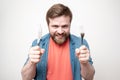 Crazy, starving bearded man holds a knife with a fork in his hands, grins and looks angrily. Concept of diet, crisis or saving Royalty Free Stock Photo