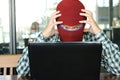 Crazy stressed masked hacker wearing a balaclava with hands on heads stealing data from laptop. Internet crime concept.