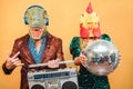 Crazy stylish people listening music with vintage boombox stereo - Fashion couple wearing t-rex and chicken mask at party fest