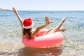 Crazy swimming with inflatable donut and christmas hat on the beach in summer sunny day Royalty Free Stock Photo