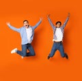 Crazy teenage guys jumping and fooling over orange background Royalty Free Stock Photo