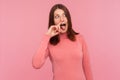 Crazy weird woman with brown hair in pink sweater holding finger in her nose showing tongue, uncultured bored girl having fun, bad