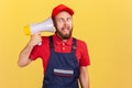 Crazy worker man holding megaphone near head, frowning face looking with crossed eyes and open mouth Royalty Free Stock Photo