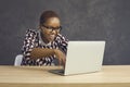 Funny crazy happy black woman in glasses sitting at desk and working on laptop computer Royalty Free Stock Photo