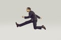 Crazy young businessman in chasing his career running fast isolated on gray background. Royalty Free Stock Photo