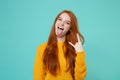 Crazy young redhead woman girl in yellow sweater isolated on blue turquoise background. People lifestyle concept. Mock Royalty Free Stock Photo