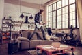 Crazy young rock musician standing on sofa and playing music