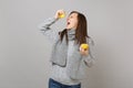 Crazy young woman in gray sweater, scarf holding lemons, squeezing lemon juice isolated on grey background. Healthy Royalty Free Stock Photo