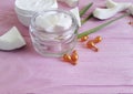 Cream, avocado on a pink wooden background, capsules