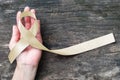 Cream awareness ribbon on helping hand support symbolic bow color for Degenerative Disc Disease (DDD) Royalty Free Stock Photo